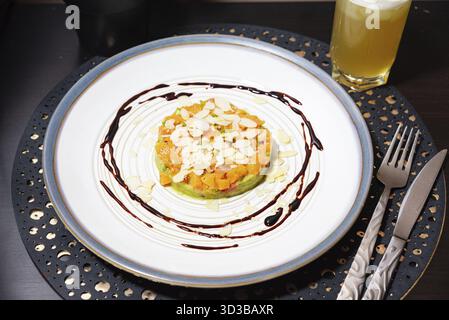 Speisen, Gourmet-Lachs-Tartar serviert auf einem Bett aus Avocado und mit Mandelscheiben garniert, garniert mit Balsamico-Glasur für gehobene Küche Stockfoto