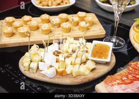 Speisen, verschiedene Käseplatten mit verschiedenen Käsewürfeln, Nüssen und süßer Marmelade, serviert auf einem Holzbrett für Vorspeisen oder Wein Stockfoto