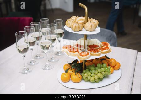 Speisen, Tiered Teller mit Häppchen, Profiteroles, Obst und Sektgläser auf einem Tisch für eine festliche Feier Stockfoto