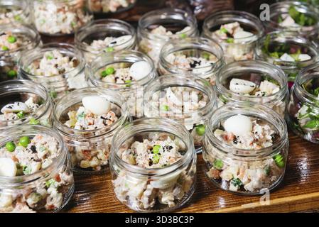 Essen, Gläser gefüllt mit cremigem Gemüsesalat, garniert mit Erbsen und Wachteleiern, für Catering oder Buffet-Service Stockfoto