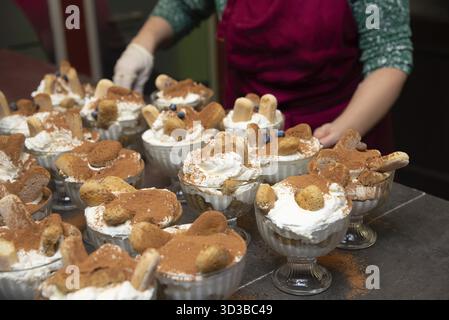 Essen, mehrere einzelne Tiramisu-Portionen in Glasschalen, garniert mit Schlagsahne, Kakaopulver und Marienfinger, servierfertig Stockfoto