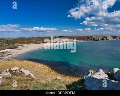 Weitwinkelblick auf eine klare türkisfarbene Bucht, Sandstrand und felsige Klippen in der Nähe von Pointe de Pen-Hir auf der Halbinsel Crozon, Bretagne, Frankreich, unter einem hellblauen Himmel. Stockfoto