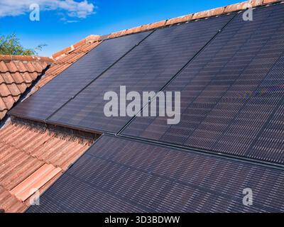 Großbritannien - 29. August 2025: Photovoltaik-Panels auf einem gekachelten Hausdach unter einem hellblauen Himmel in Großbritannien, die saubere Energie und moderne Wohneffizienz veranschaulichen. Stockfoto