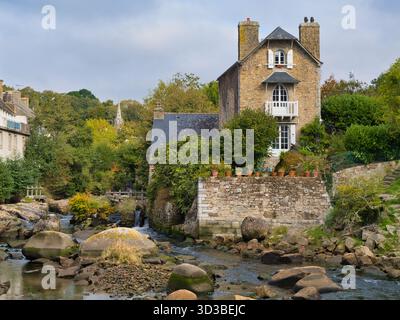 Pont-Aven, Frankreich - 28. September 2025: Der Fluss Aven schlängelt sich unter weichem Herbstlicht an einem Steinhaus und üppigen Gärten in Pont-Aven, Bretagne, Frankreich. Stockfoto