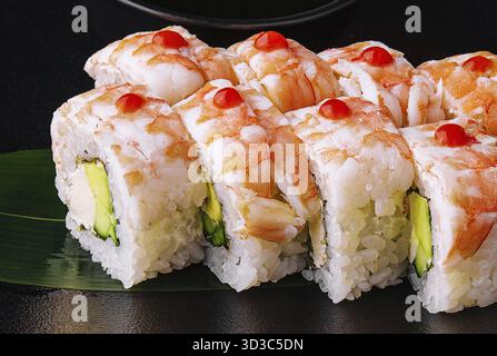 Essen, Sushi-Rolle bedeckt mit Garnelenfleisch auf schwarzer Keramikplatte Stockfoto