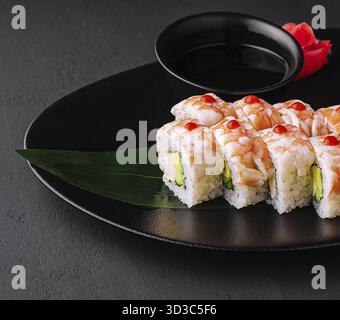 Essen, Sushi-Rolle bedeckt mit Garnelenfleisch auf schwarzer Keramikplatte Stockfoto