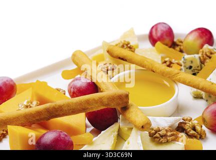 Essen, Käseplatte mit Honig, Nüssen und roten Trauben Stockfoto