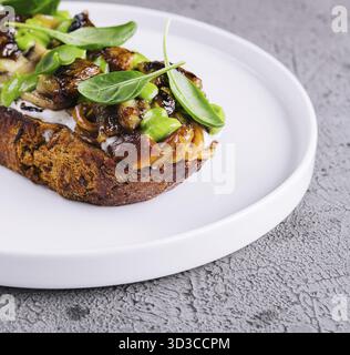 Essen, Toast mit gebratenen Stachelpilzen auf weißem Teller Stockfoto