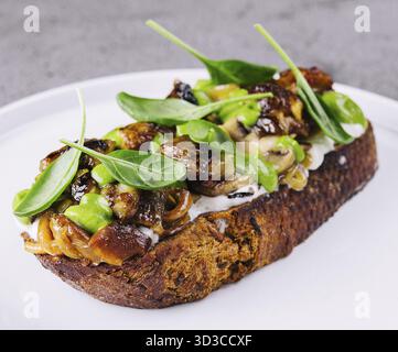 Essen, Toast mit gebratenen Stachelpilzen auf weißem Teller Stockfoto