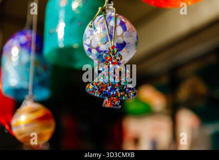 Farbenfrohe weihnachtsdekoration aus Glas hängt auf dem sonnendurchfluteten Markt. Stockfoto
