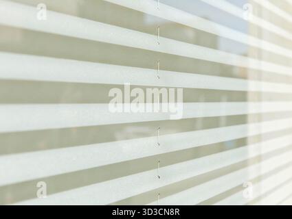 Horizontale weiße Jalousien mit weichen Licht- und Schattenmustern. Stockfoto