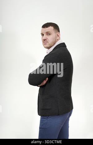 Porträt eines eleganten jungen Geschäftsmannes, der mit überkreuzten Armen steht Stockfoto