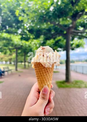Die Hand hält draußen eine Eiscreme Stockfoto
