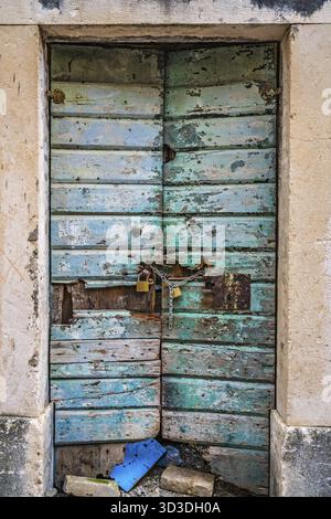 Mit Vorhängeschlössern und Kette alten grünen beschädigte Türen aus Holz in einem der Gebäude in Kotor, Montenegro gesperrt Stockfoto