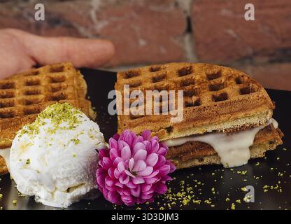 Essen, belgische Waffeln mit Eis auf schwarzem Teller Stockfoto