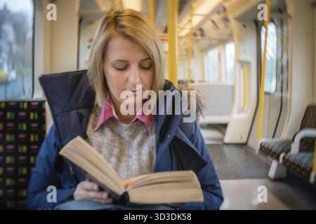 Blond kaukasische Frau mit Buch beim Pendeln in London zu arbeiten Stockfoto
