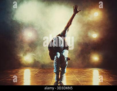 Junger Mann tanzt im Club mit Licht und Rauch. Tätowierung am Körper Stockfoto