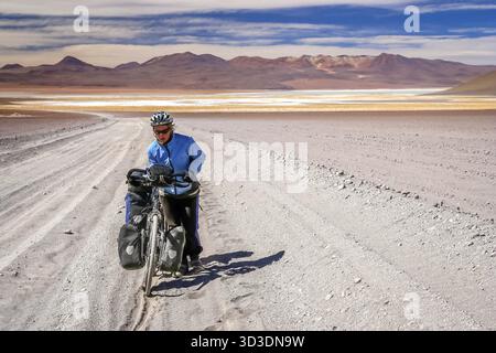 Frau Radrennfahrer kämpfen und schieben ihr Fahrrad auf Wellpappe Sandweg im Altiplano in Bolivien Stockfoto