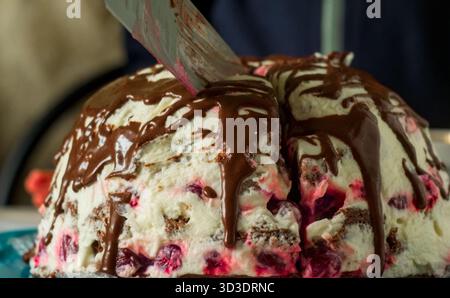 Cutting Chocolate Volcano Beeren Cake - hausgemachte Kuchen mit weißem Sauerrahm Zuckerguss, Beeren und Schokoladennebel Stockfoto