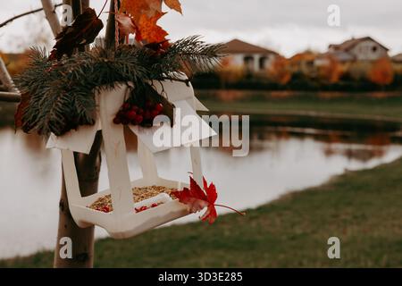 DIY Vogelfutter aus recycelter Plastikflasche, verziert mit Herbstblättern und Kiefernzweigen, die an einem Baum in der Nähe des Sees hängen. Umweltfreundliches Konzept, Crea Stockfoto