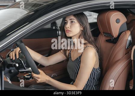 Junge asiatische Frau sitzt in Luxus-Auto in der Garage vor dem Starten des Motors und fahren Stockfoto