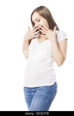 Porträt einer fröhlichen schwangeren Frau mit erhobenen Armen, die staunend nach unten blickt. Studio-Aufnahme Stockfoto