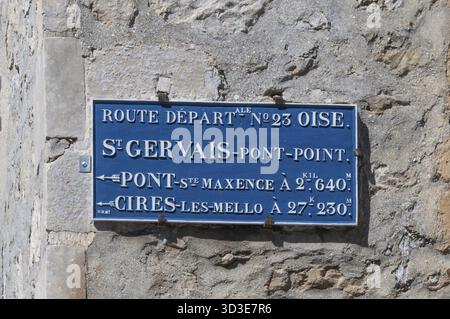 Historischer blauer Wegweiser an einer Steinmauer. Das Schild mit der Inschrift ROUTE VERLÄSST NÂ° 23 OISE und die Stadt ST GERVAIS-PONT-POINT zeigt die Entfernungen an Stockfoto