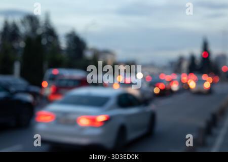 Starker Stadtverkehr, Rückblick der Autos bei Dämmerung/Abend, rote Bokeh-Bremslichter auf dunkelblauem Hintergrund, verschwommene Rush Hour, moderne Stadt Stockfoto