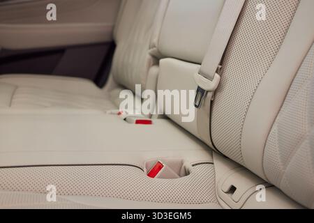 Armlehne mit Getränkehalter innen. Bequeme Beifahrersitze und Armlehne in weiß in Leder. Innenraum aus weißem Leder des modernen Luxuswagens. Modernes Auto Stockfoto