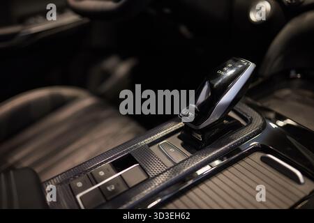 Wählautomatik mit Leder im Innenraum eines modernen, teuren Autos. Der Hintergrund ist unscharf. Schwarzes und braunes Lederauto. Stockfoto