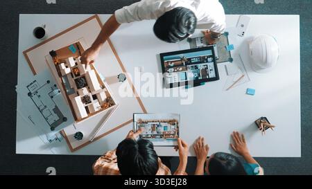 Top-Down-Ansicht eines Bauarchitekten, der den Projektplan betrachtet, während er dem Investor am Besprechungstisch anwesend ist. Luftaufnahme eines erfahrenen Konstrukteurs erläutern Stockfoto