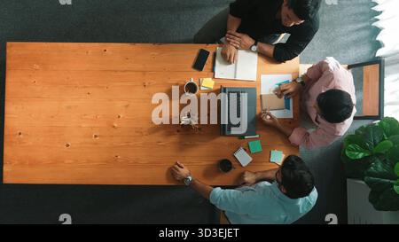 Top-Down-Luftaufnahme des Geschäftsteams, die sich einen Finanzdiagramm ansieht und gleichzeitig die Hand schüttelt, um eine Vereinbarung zu treffen. Unterschiedliche Mitarbeiter planen Marketingstrategie Stockfoto