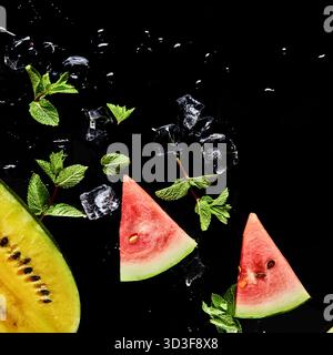 Nahaufnahme von lebendigen Wassermelonenscheiben, frischen Minzblättern und Eiswürfeln vor dunklem Hintergrund, was ein kühles, erfrischendes Getränk andeutet. Stockfoto