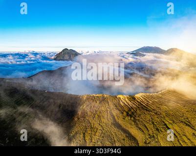 Aus der Vogelperspektive auf die Felsenklippe am Kawah Ijen Vulkan mit türkisfarbenem Schwefelwassersee bei Sonnenaufgang. Fantastischer Blick auf die Naturlandschaft in Ost-Java, Indonesien. Natu Stockfoto