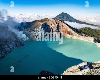Aus der Vogelperspektive auf die Felsenklippe am Kawah Ijen Vulkan mit türkisfarbenem Schwefelwassersee bei Sonnenaufgang. Fantastischer Blick auf die Naturlandschaft in Ost-Java, Indonesien. Natu Stockfoto