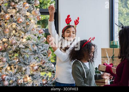 Vielfältige Familiengeschenke im Wohnzimmer in der Nähe des Weihnachtsbaums mit Geschenken, Geweih-Haarbändern Stockfoto