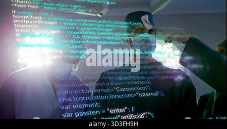 Demonstrieren eines Mannes, der ein VR-Headset trägt, der mit projiziertem Code im High-Tech-Labor interagiert, mit Kabeln Stockfoto