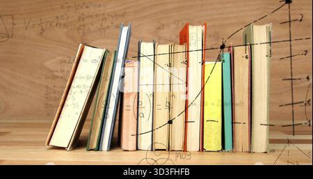 Zeigt eine Reihe von Hardcover-Büchern, die im Studium auf einer hölzernen Oberfläche stehen und mit mathematischen Diagrammen überlagert sind Stockfoto