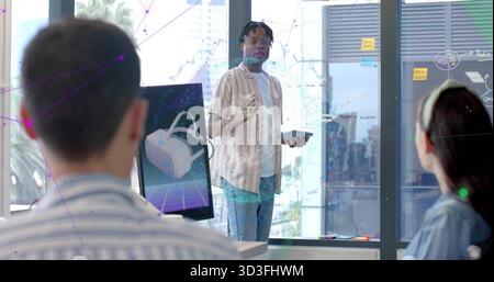 Stehender Mann mit Tablet und Gesten in modernem Büro, VR-Monitor, Glasbrett, gestreiftes Hemd Stockfoto