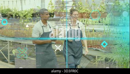 Walking-Kindergärtner mit Schürzen, die Setzlinge im Gewächshaus mit Tablet und Smartphone inspizieren Stockfoto