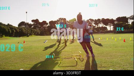 Sprintende Fußballspielerin, die Hürdenübung auf dem goldenen Hürdenfeld durchführt, mit Kegeln Stockfoto