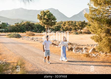 Ein Paar genießt einen Spaziergang entlang eines sonnigen Pfades in der Türkei, umgeben von malerischen Bergen und üppigem Grün, die Romantik und Ruhe in einem verkörpern Stockfoto
