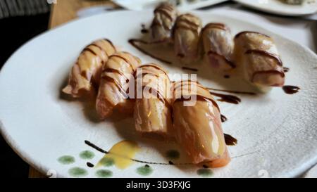 Ein wunderschön überzogenes Gericht mit Flammennigiri mit glasiertem Lachs. Das zarte Aussehen und die glänzende Oberfläche machen ihn zu einer ansprechenden Wahl für weiche Stoffe Stockfoto