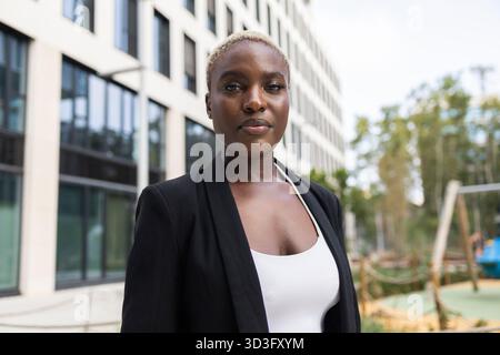 Geschäftsfrau und CEO stehen selbstbewusst vor einem modernen Bürogebäude. Sie strahlt Führung und Professionalität aus und zeigt ihre Rolle in A c Stockfoto