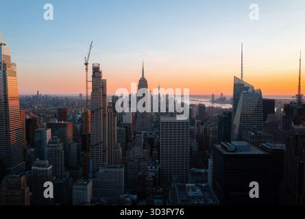 Ein atemberaubender Blick auf New York City bei Sonnenuntergang mit berühmten Wahrzeichen wie dem Empire State Building und dem One World Trade Center, das Long SHA ausstrahlt Stockfoto