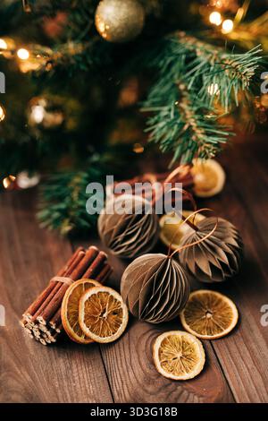 Eine gemütliche Weihnachtsszene mit getrockneten Orangenscheiben und Zimtstäbchen unter einem wunderschön beleuchteten Baum, die traditionelle und natürliche Weihnachtsdeco zeigt Stockfoto