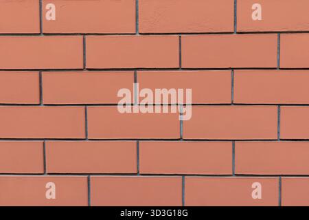 Ein Nahbild einer roten Ziegelwand mit einem klassischen rechteckigen Muster mit sichtbaren Mörtellinien. Die Ziegel haben eine glatte Textur, wodurch ein entsteht Stockfoto
