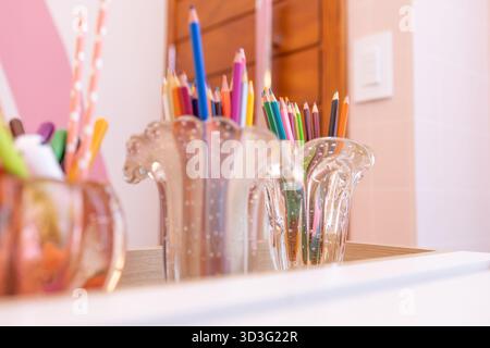 Ein bezaubernder Kunstraum in einem kleinen luxuriösen Kinderzimmer mit farbenfrohen Bleistiften in eleganten Glashaltern, die an den sanften rosa Wänden platziert sind und einen vib-Stil schaffen Stockfoto