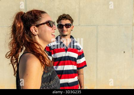 Ein lebhaftes LGBT-Paar genießt einen sonnigen Tag in der Stadt und zeigt seinen einzigartigen Stil und seine fröhliche Verbindung. Authentische Ausdrucksformen und Moderne Stockfoto