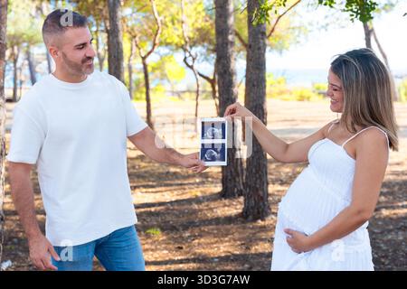 Schwangere Paare mit Ultraschallbild eines zukünftigen Babys im Freien. Stockfoto